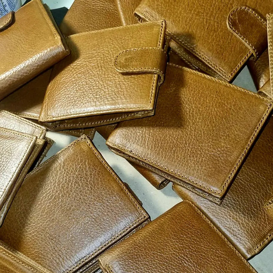 Pile of brown, tan Businessmen's leather wallets on a light surface made by Cape Masai Leather.