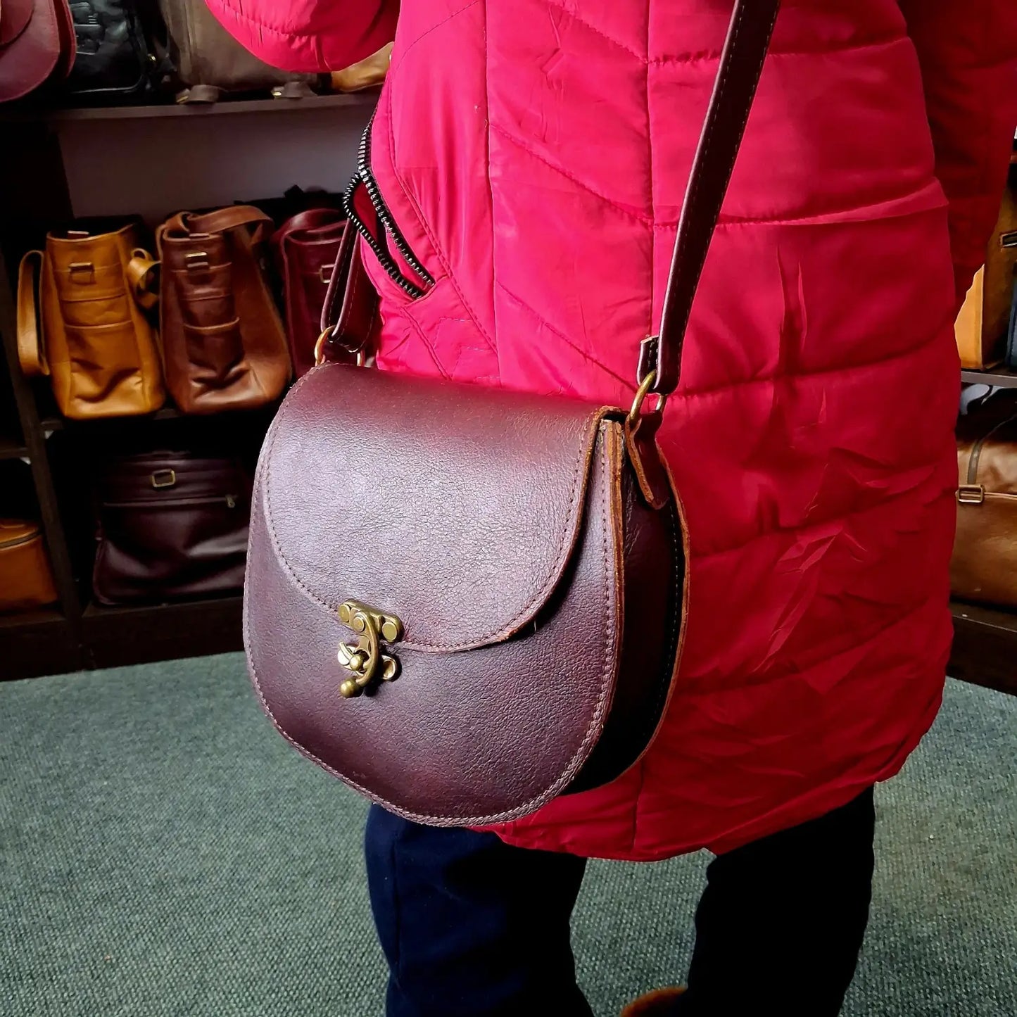Person wearing a red jacket holding a dark tan D Bag big leather bags