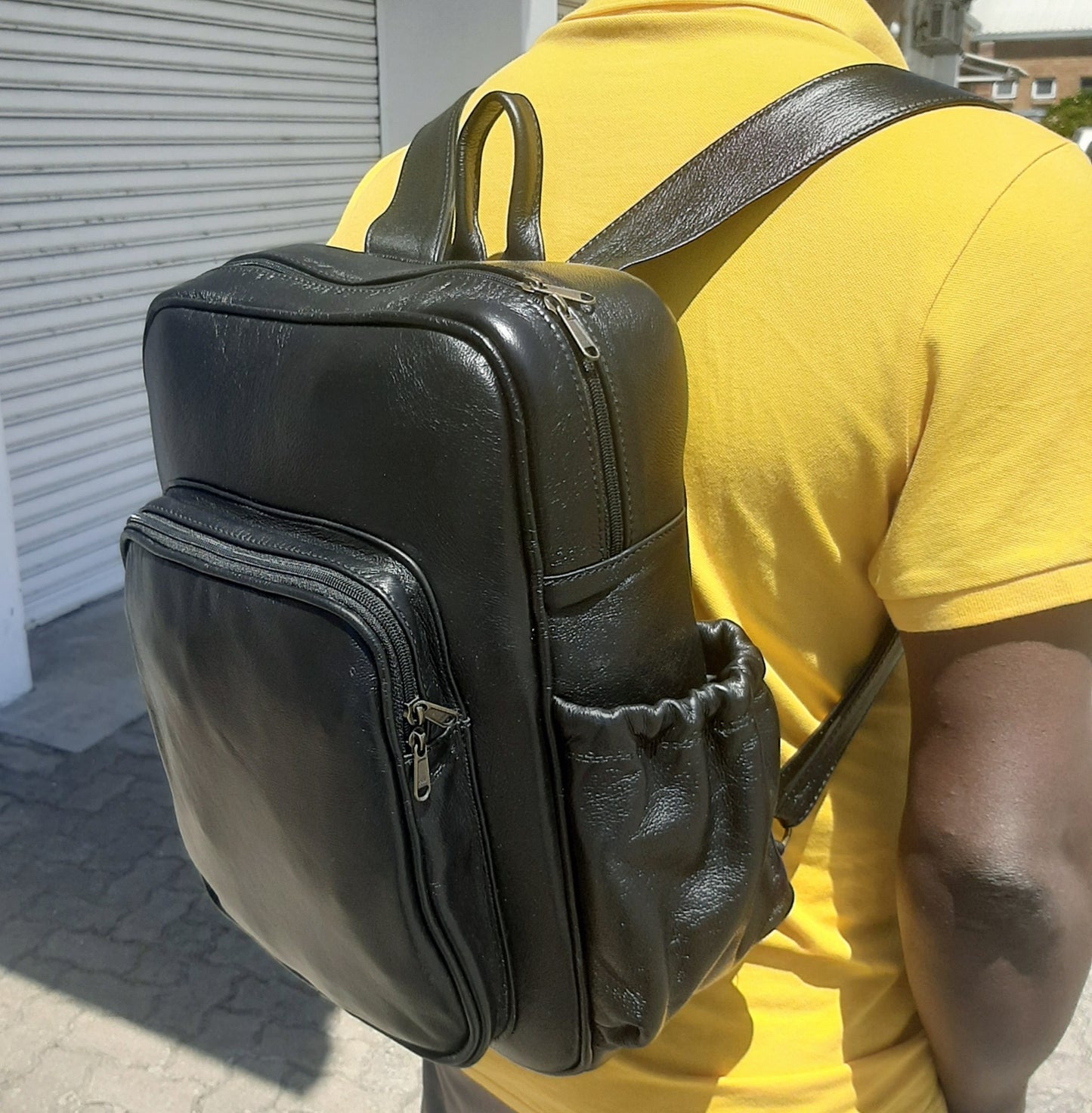 A man carrying geniune leather Everyday Laptop Backpacks 15" with side pockets in black colour from Cape Masai Leather