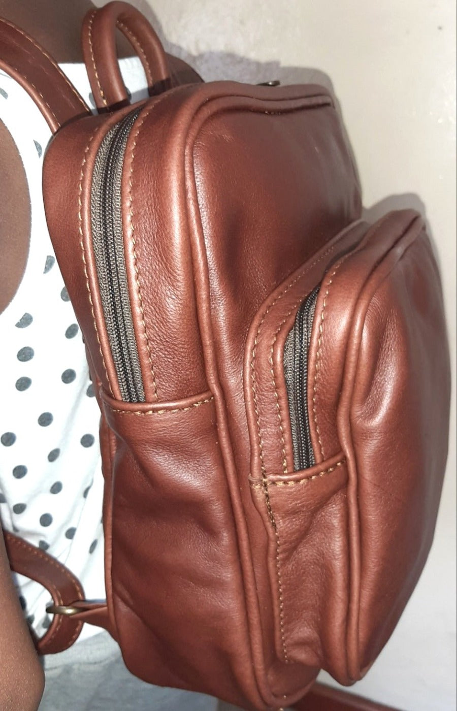 A beautiful Masai lady carrying beautiful oxblood a small Everyday leather backpack for women from Cape Masai Leather.