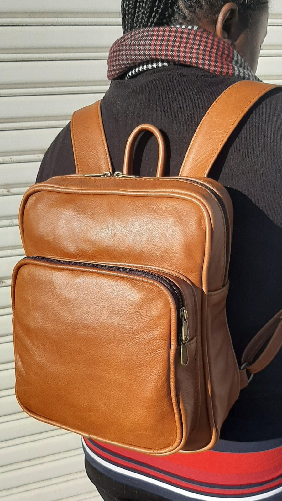 A beautiful Masai lady carrying beautiful ginger tan a small Everyday leather backpack for women from Cape Masai Leather.