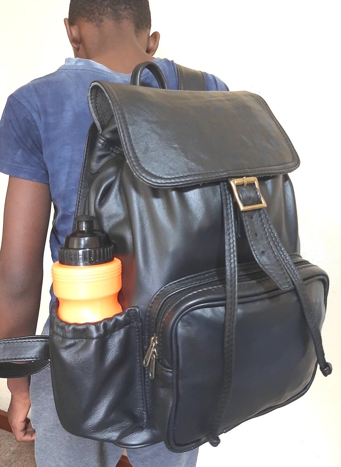 A boy boarding flight with beautiful Woodlands buffalo leather backpack with flap xl on her back from Cape Masai Leath