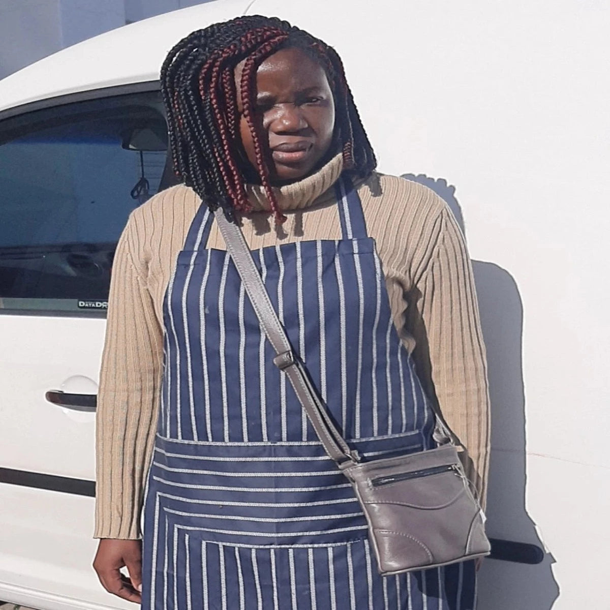 A lady carring sling bag short gray next to Cape Masai leather van