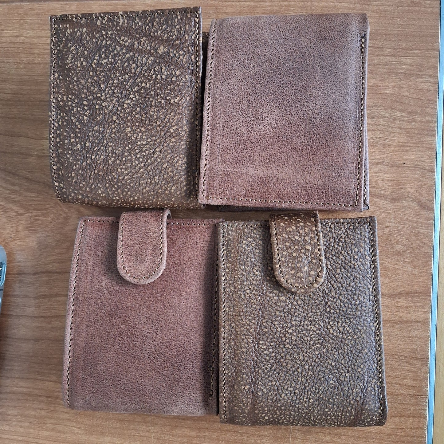 Four brown leather pouches on a wooden surface