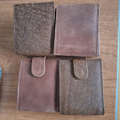 Four brown leather pouches on a wooden surface