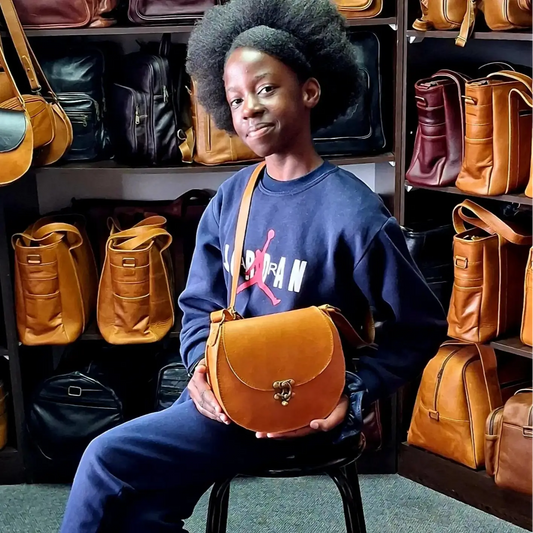 A girl wearing blue Jordan sitting a stool carrying D Bag big leather bags in light 