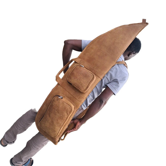 A man carrying on his back Cape Masai Leather rifle bag / guitar case in bitter brow on a white background