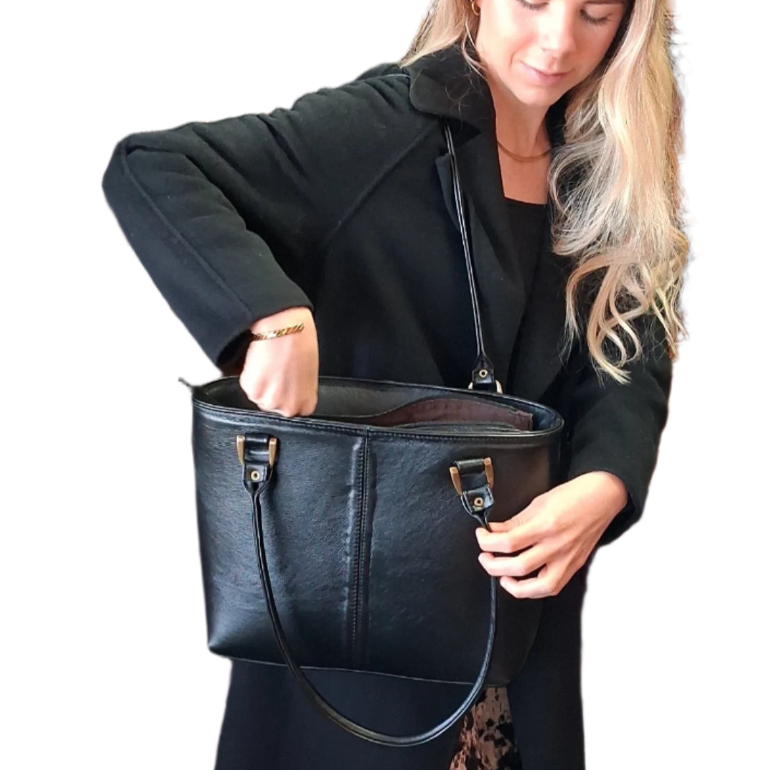 Woman carrying and opening a black Michelle leather tote bag on a white background while holding one handle.