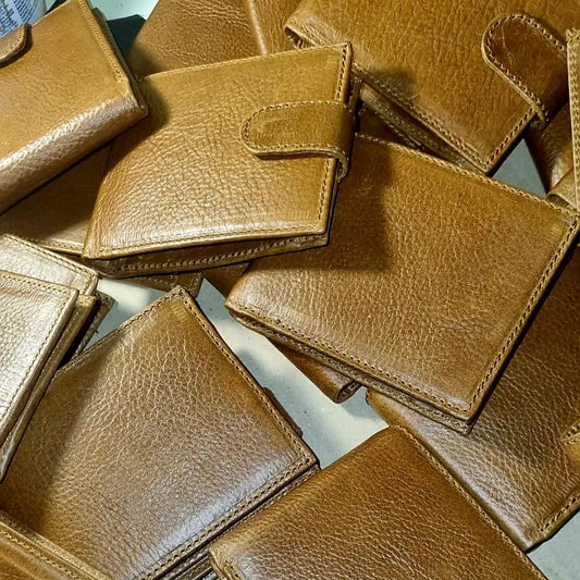 Pile of brown, tan Businessmen's leather wallets on a light surface made by Cape Masai Leather.