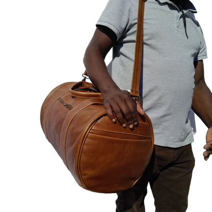 A man carrying Duffle travel bag small pecan tan from Cape Masai Leather 