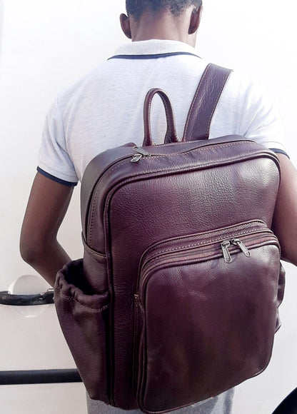 A boy carrying genuine leather Everyday Laptop Backpacks 15" in dark tan with side pockets from Cape Masai Leather