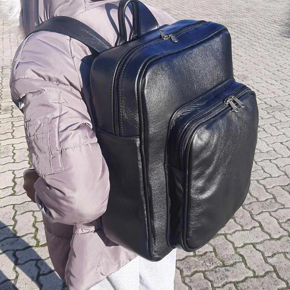 A girl carrying genuine leather Everyday Laptop Backpacks 15" with side pockets in black colour from Cape Masai Leather