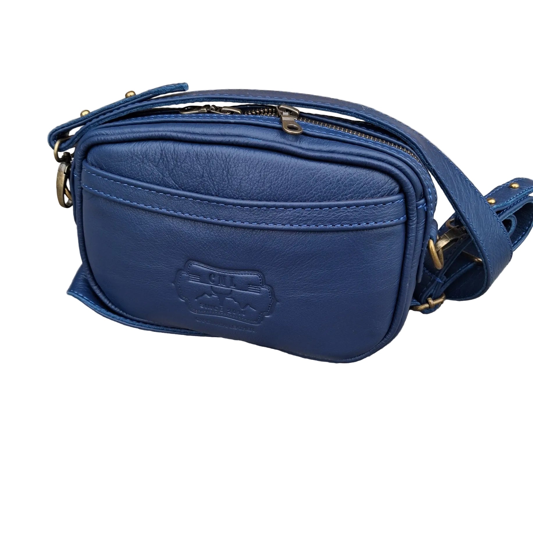 Lady X Leather Sling in light navy-blue colour crossbody bag with gold-tone hardware, featuring an embossed CML logo on the front, resting on a paved stone surface.