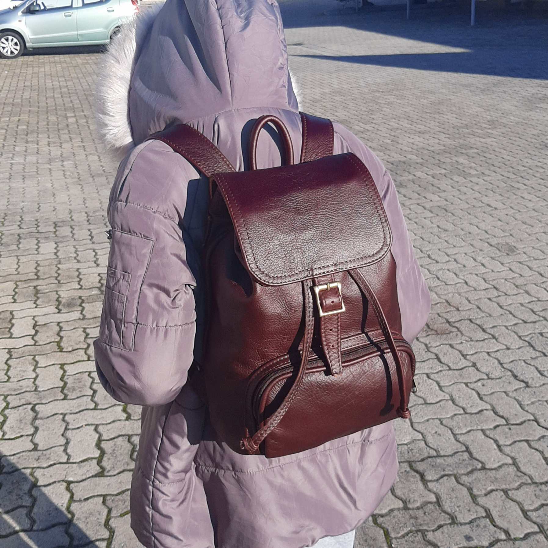 A young lady carrying a beautiful genuine leather backpack with flap in dark tan from Cape Masai Leather 