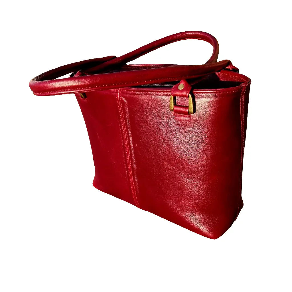 A cherry red Michelle leather tote bag on a white background made by Cape Masai Leather with handles crossed on top