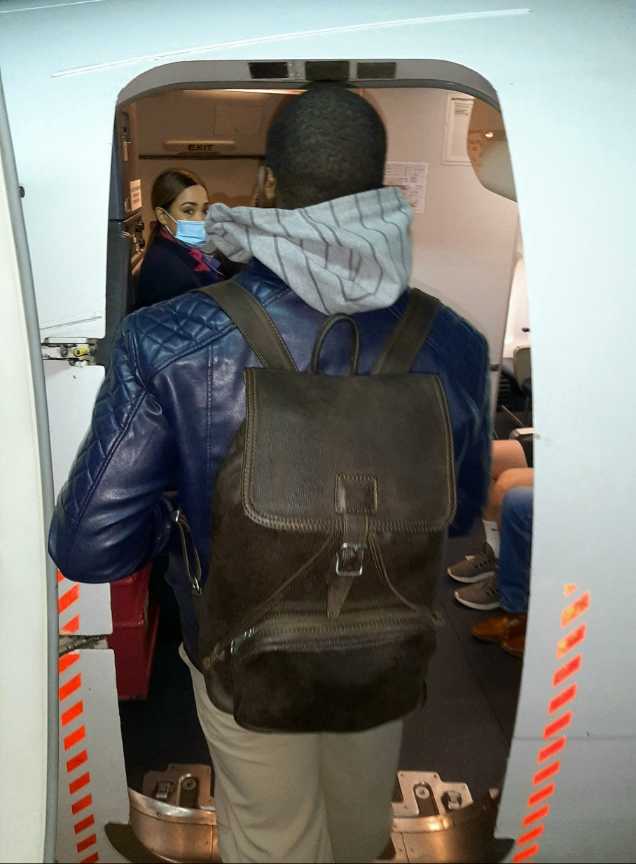 A man  boarding flight with beautiful Woodlands buffalo  leather backpack with flap xl on her back from Cape Masai Leath