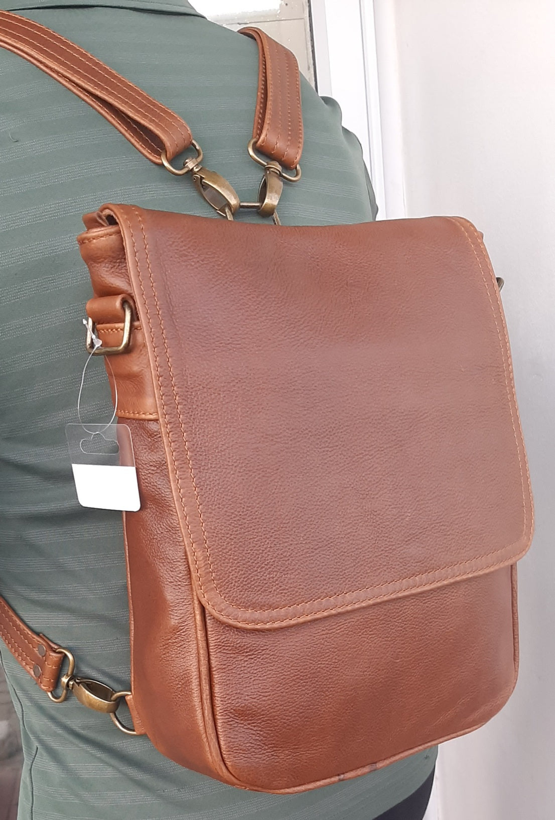 A man carrying a beautiful genuine leather hand made 2 in 1 Am messenger backpack in pecan tan 