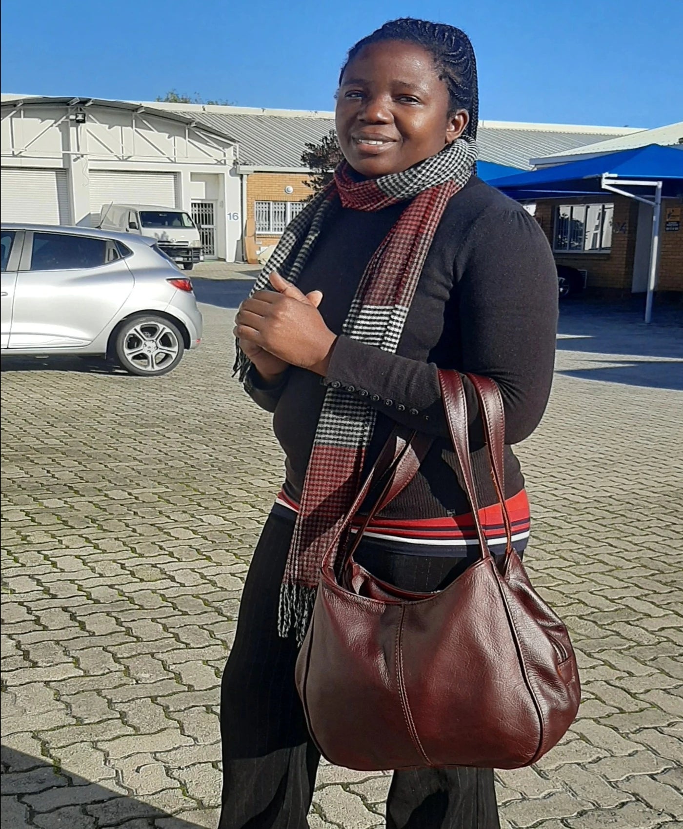 A smiling lady carrying beautiful dark tan corra leather bag from Cape Masai Leather .  