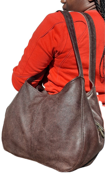 A smiling lady carrying beautiful woodlands buffallo corra leather bag from Cape Masai Leather .