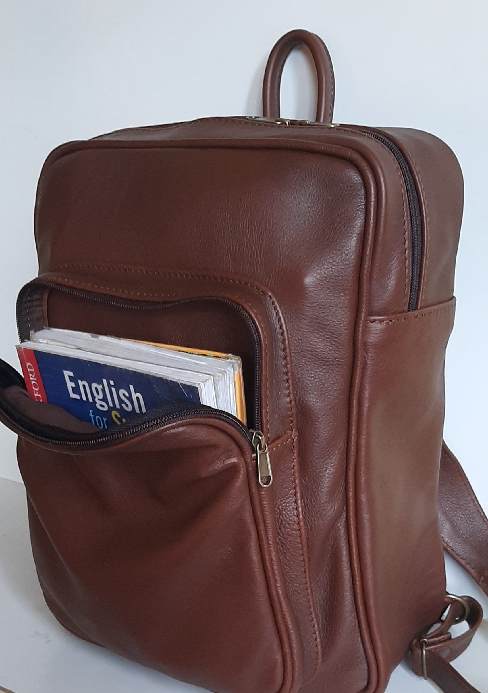 A beautiful genuine leather backpack with A4 size books in the front pocket , designed and made by Cape Masai leather 