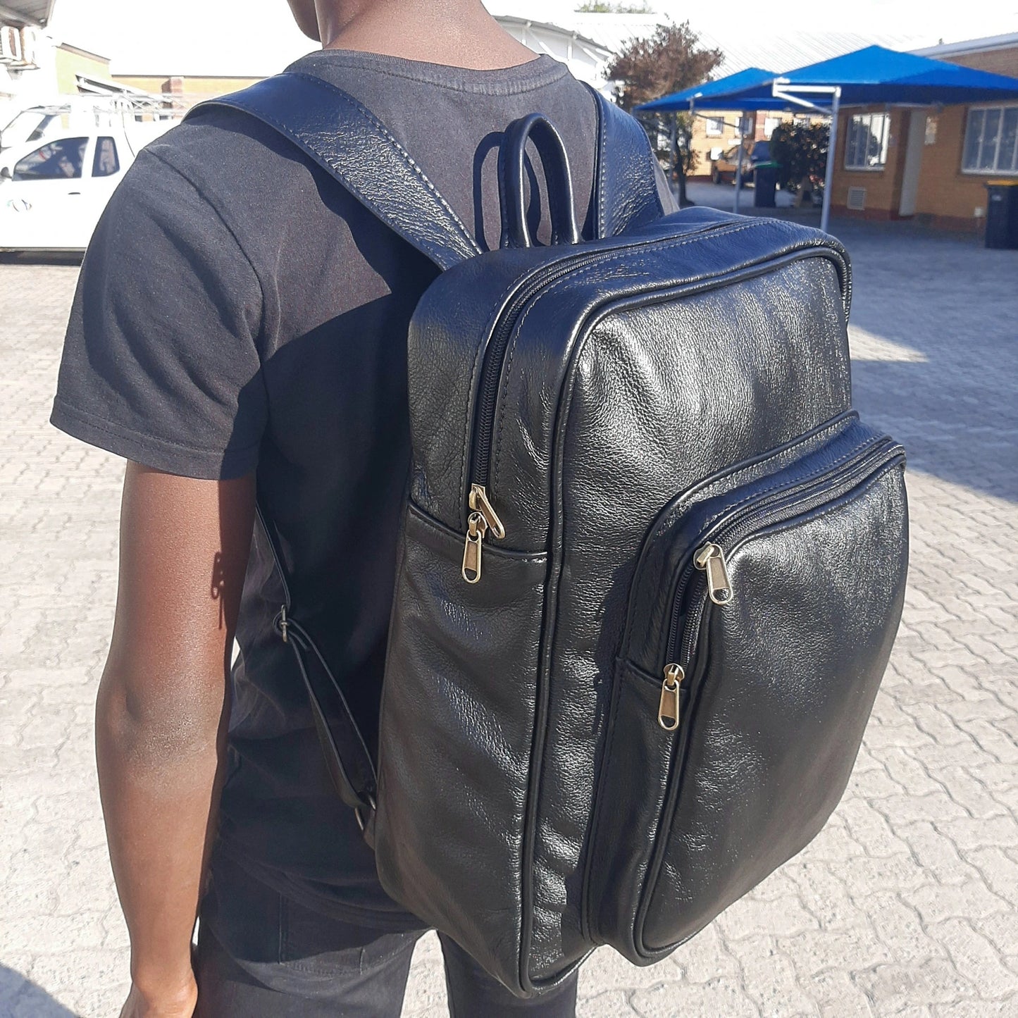 A boy carrying Everyday Leather Backpacks XL in black colour from Cape Masai Leather 