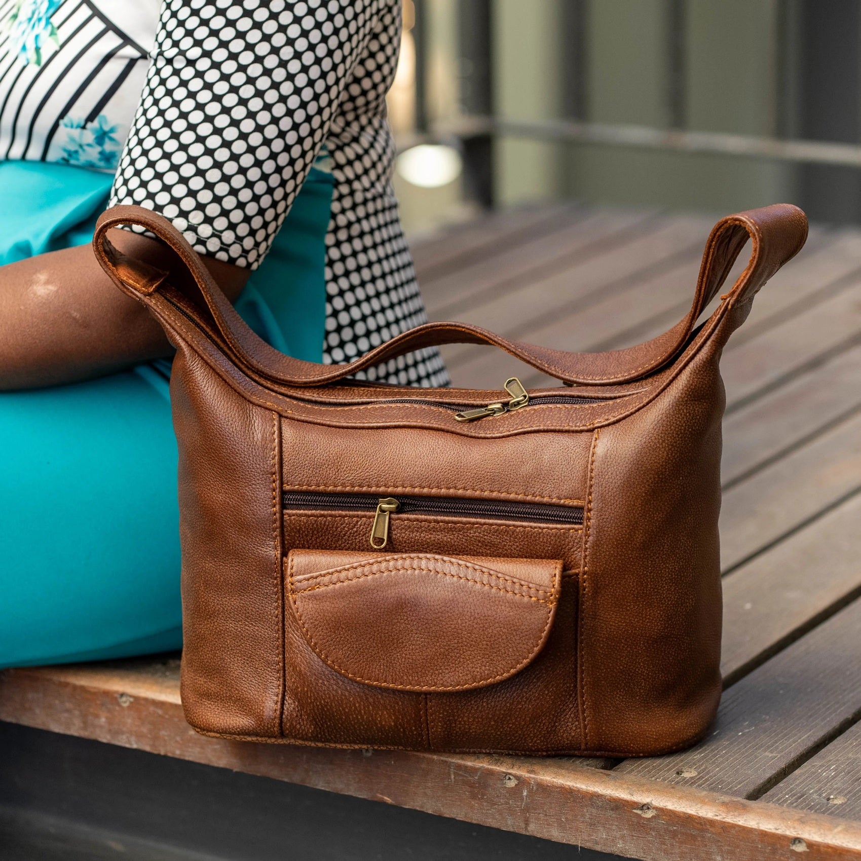 A lady sitting next to her Gb7 leather bags with flap in bitter brown made by cape Masai Leather