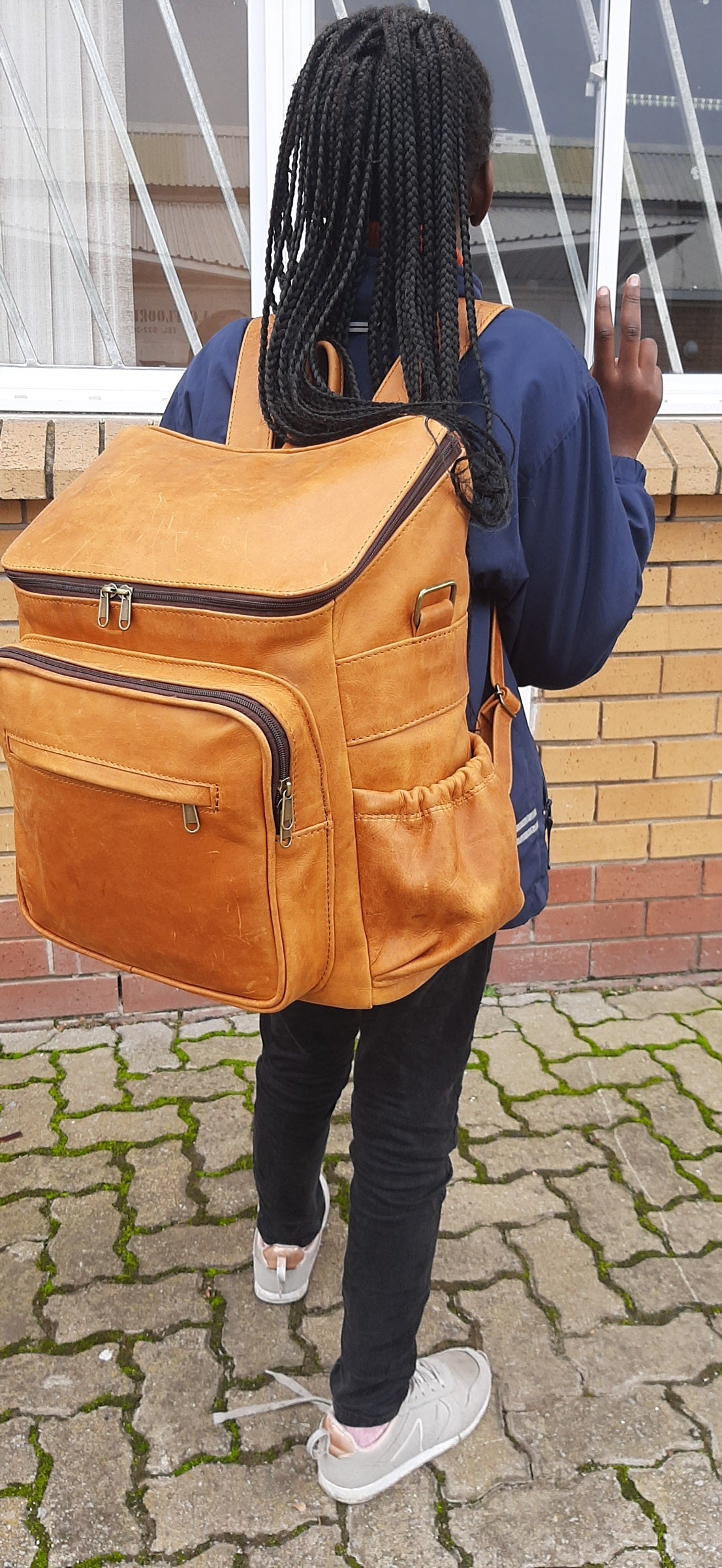 A little girl carrying a beautiful baby backpack - Diesel toffee tan colour