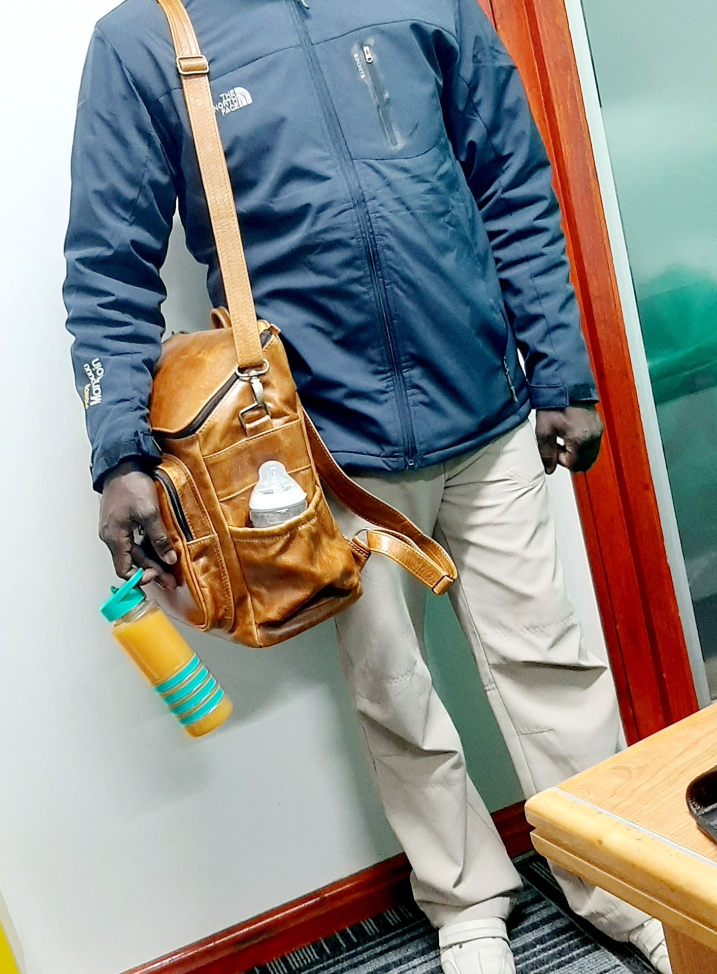 A man carrying a beautiful baby backpack in light tan colour made by Cape Masai Leather