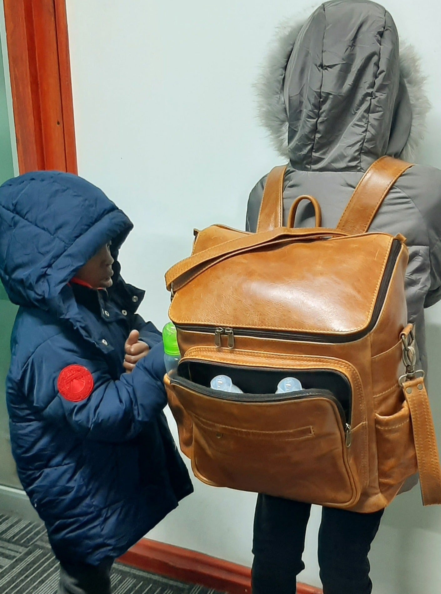 A little girl carrying a beautiful baby backpack - light tan colour