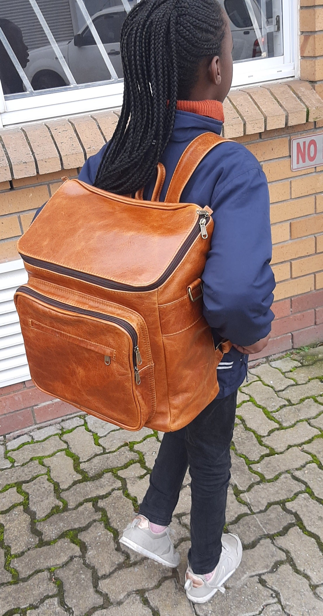 A little girl carrying a beautiful baby backpack - light tan colour 